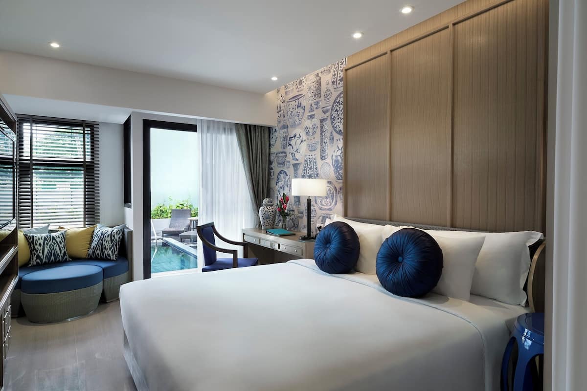 Une chambre d’hôtel moderne, dotée d’un grand lit, d’un bureau, d’une chaise et offrant une vue sur la piscine.