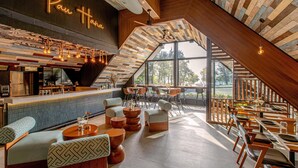 A modern interior with a bar area, seating, and large windows. - OUTRIGGER Surin Beach Resort (Choeng Thale)