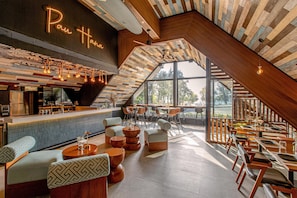 A modern interior with a bar area, seating, and large windows.