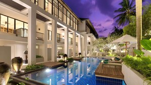 A modern hotel with a swimming pool, outdoor seating, and a well-lit balcony area. - OUTRIGGER Surin Beach Resort (Choeng Thale)