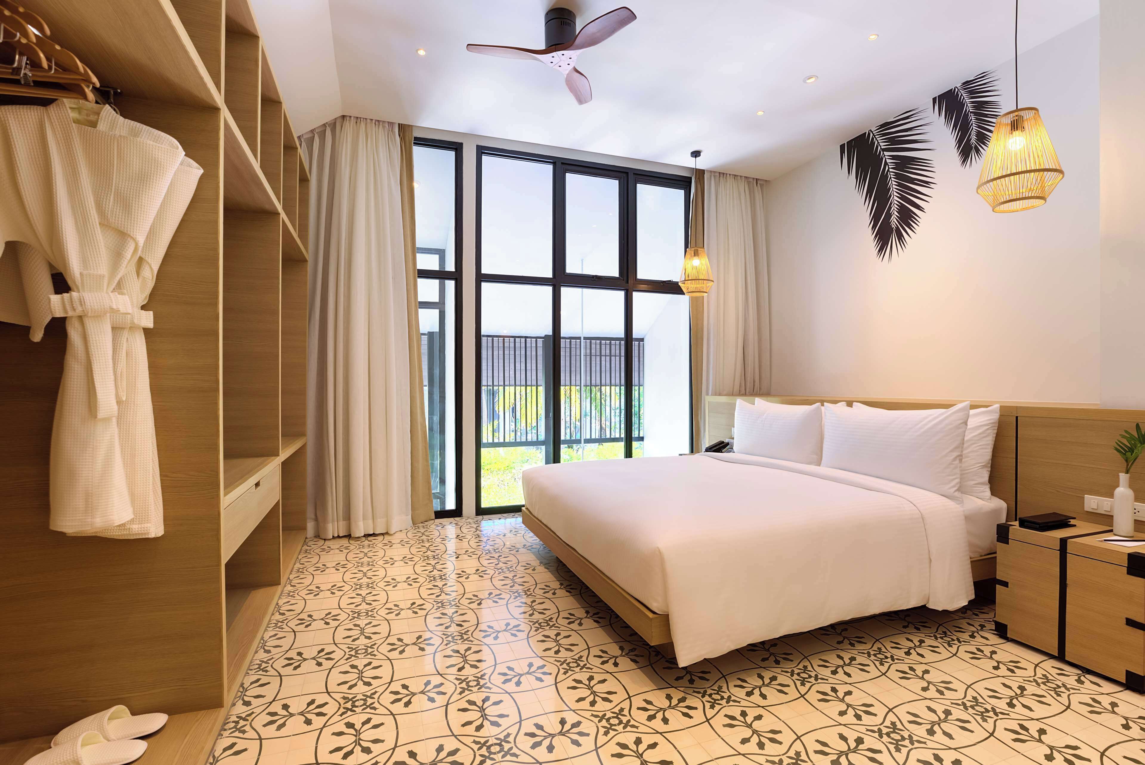 A hotel room with a bed, a wardrobe, a ceiling fan, and a view through the window.