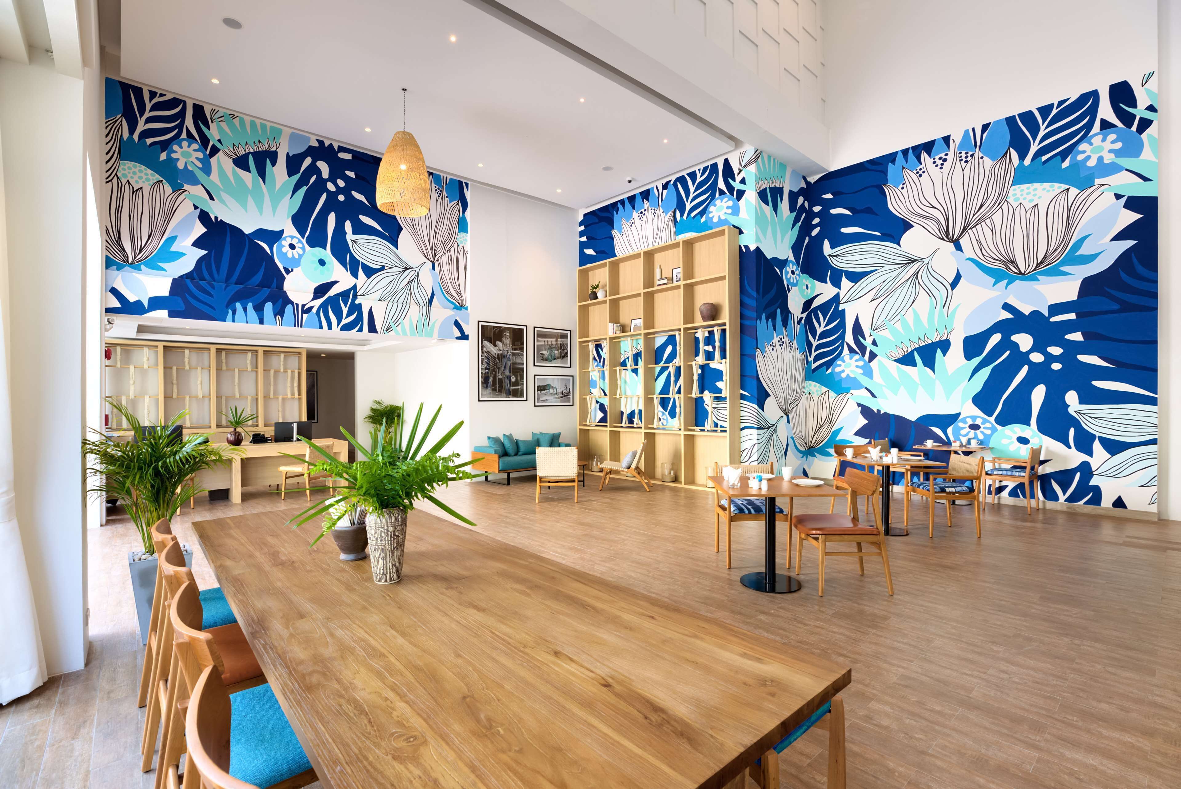 A spacious room with a wooden dining table, chairs, a bookshelf, and a large wall mural.