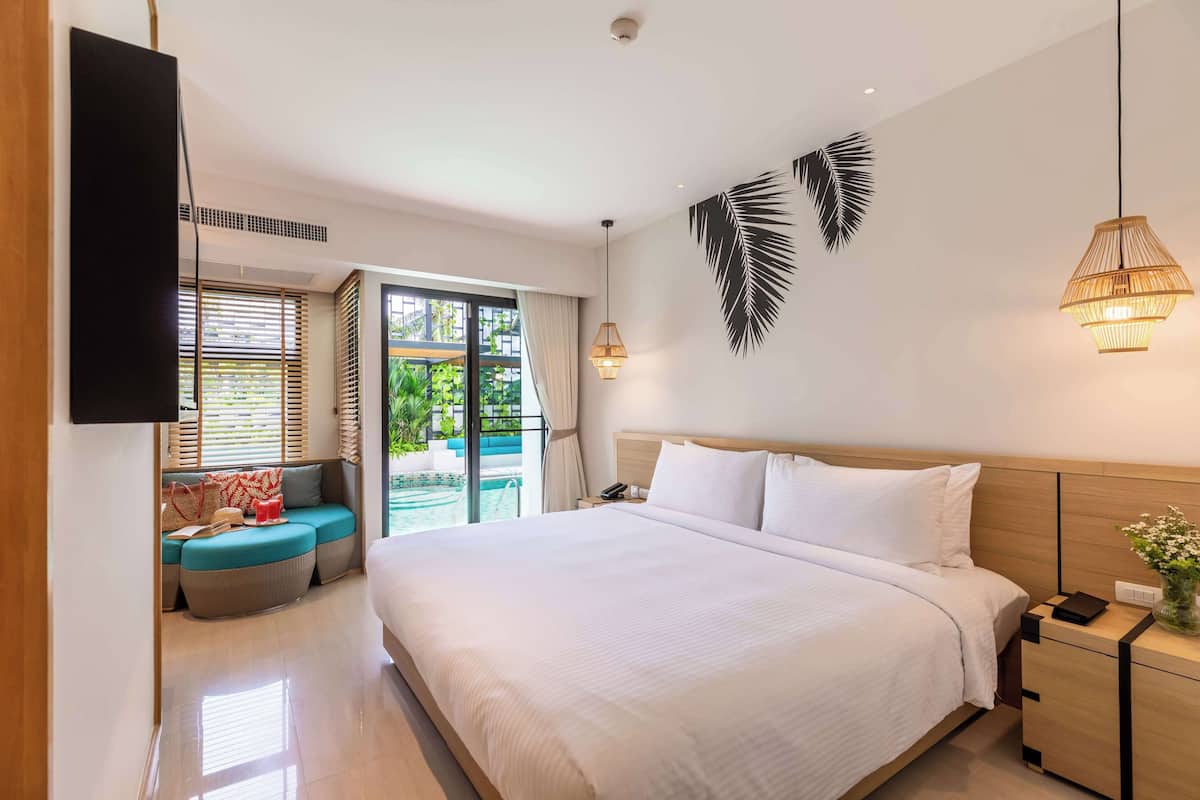 Una habitación de hotel moderna con una cama grande, un área de descanso con vistas y un televisor montado en la pared.