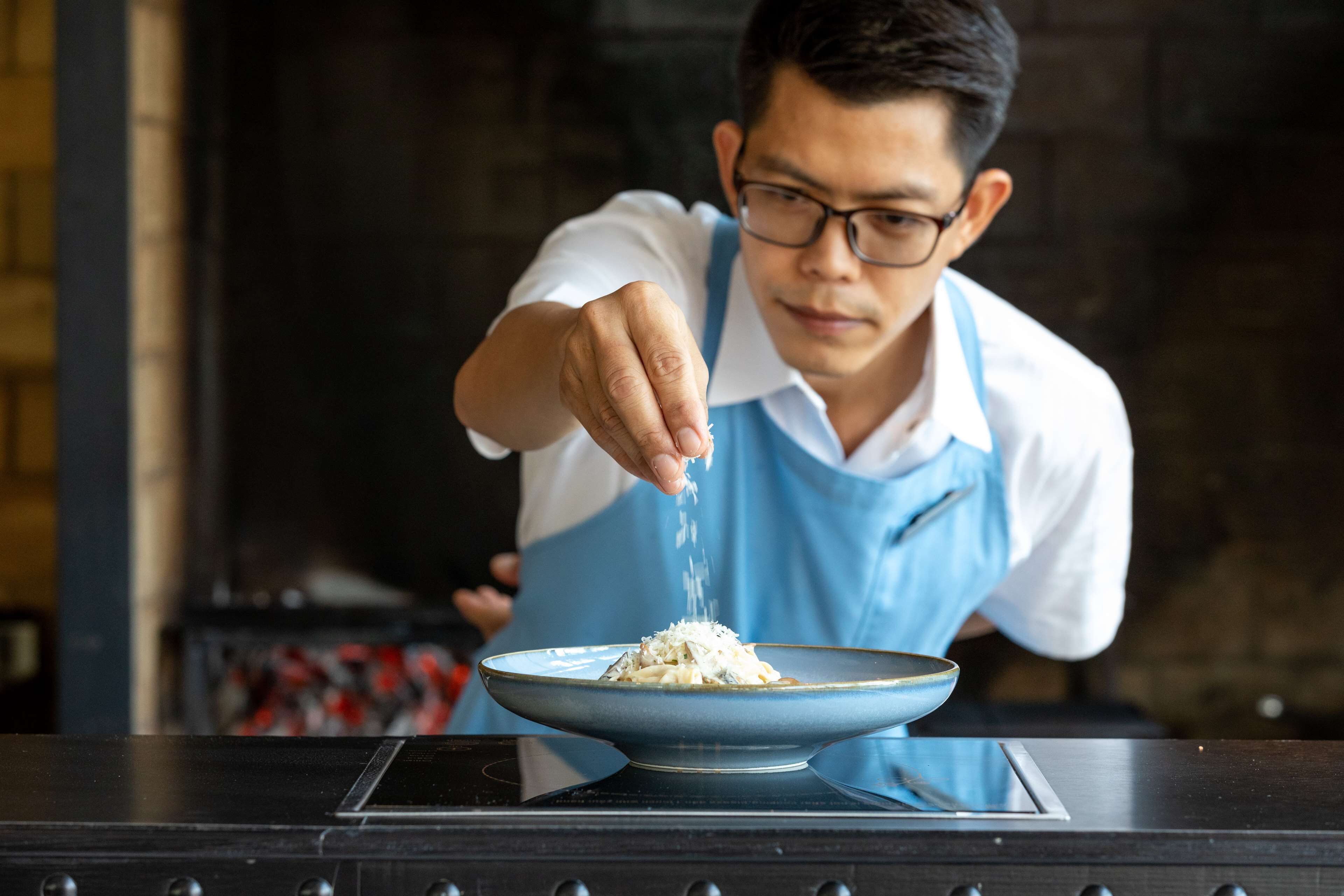 A person seasoning food on a stove.
