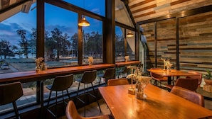 A restaurant with large windows, wooden tables, and chairs. - OUTRIGGER Surin Beach Resort (Choeng Thale)