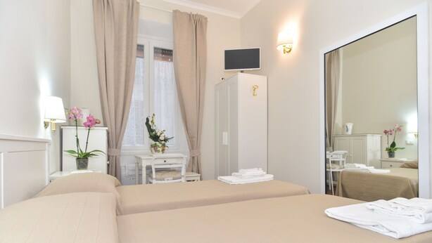 A hotel room with two beds, a desk with a chair, a TV, and a large mirror. - Romebest (Rome)