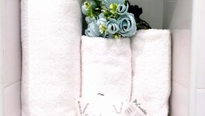 A white cabinet with three rolled white towels and a bouquet of blue flowers. - Romebest (Rome)