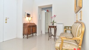 A room with a wooden cabinet, a table with a vase, a sofa, and a mirror on the wall. - Romebest (Rome)