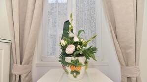 A white table with a potted plant featuring flowers and leaves. - Romebest (Rome)