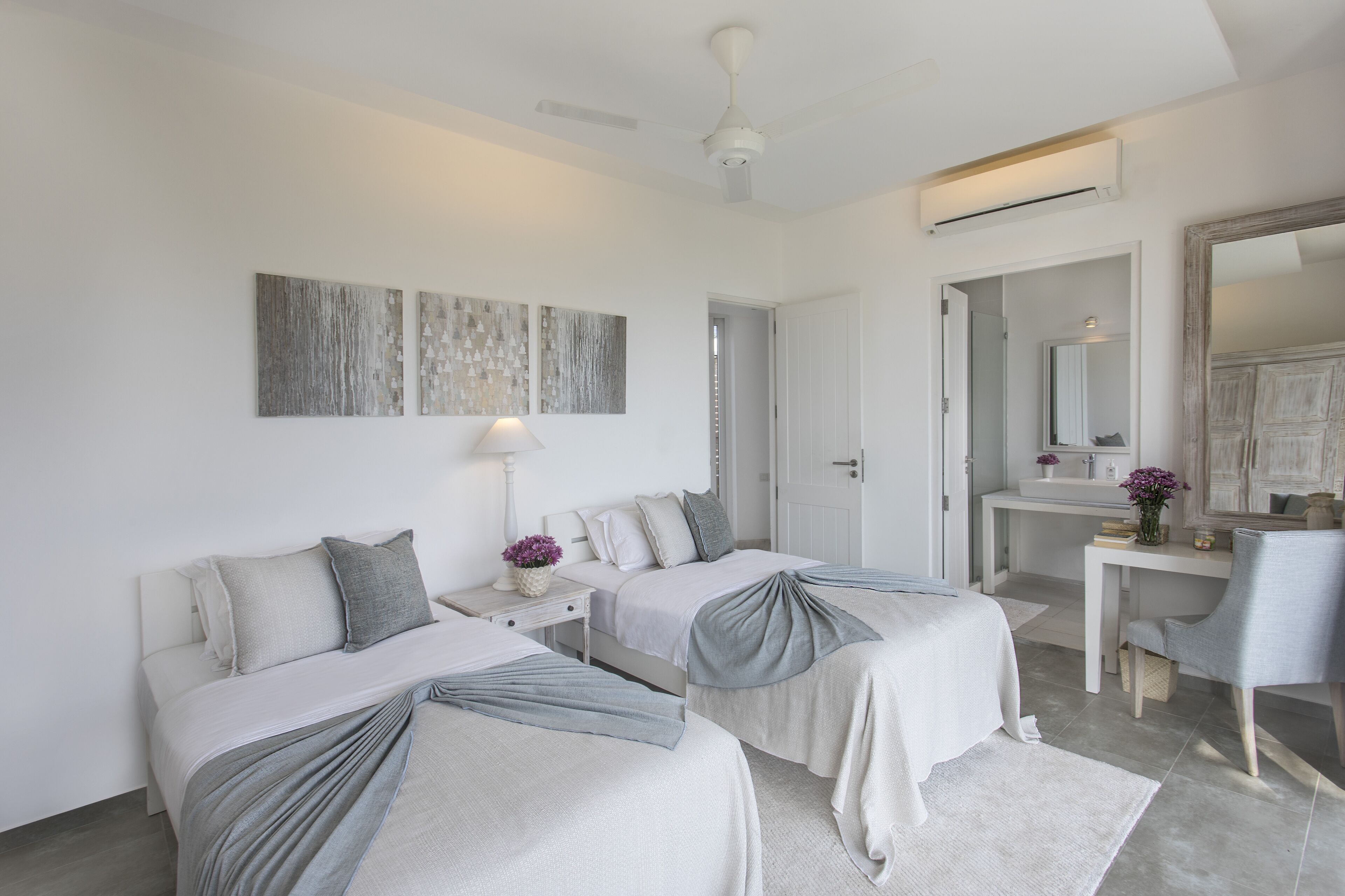 Une chambre d’hôtel moderne équipée de deux lits, d’un bureau, d’une chaise et d’un grand miroir.
