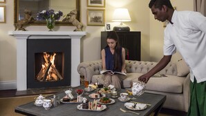 A room with a fireplace, a sofa, and a table set with tea and pastries. - Hill Rise Luxury Villa & Stables by Edwards Collection (Nuwara Eliya)
