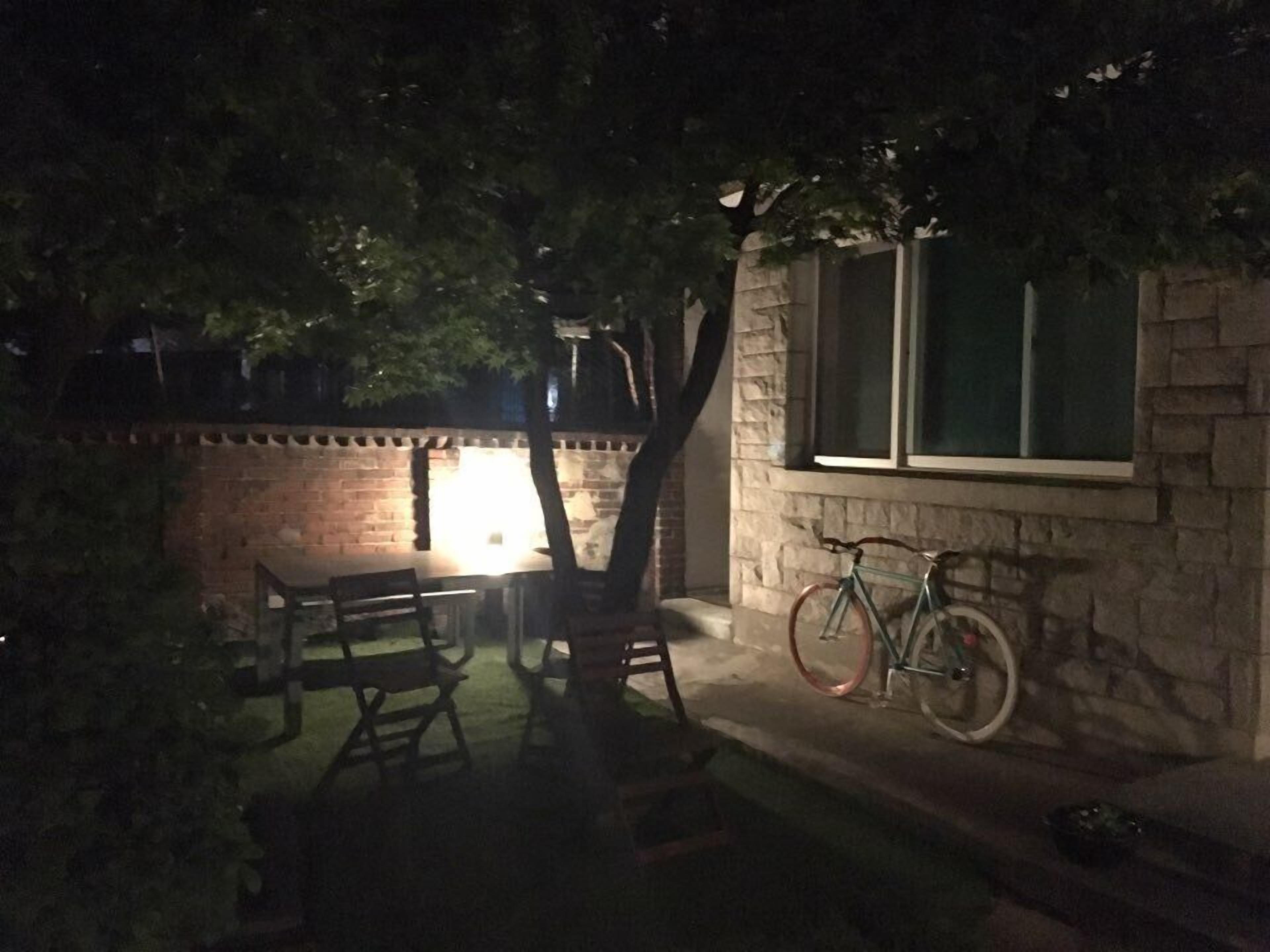 An outdoor patio area with a brick wall, a table, chairs, and a bicycle leaning against the wall.