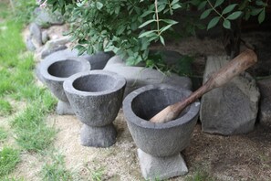 A set of stone mortar and pestle with a wooden handle, placed on a stone base. - Hans House (Seoul)