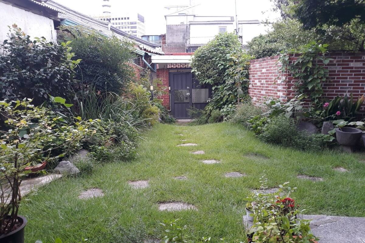 Un piccolo giardino recintato con un vialetto lastricato che porta a un cancello.