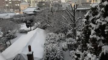 Un edificio tradicional japonés con tejado nevado y árboles circundantes.