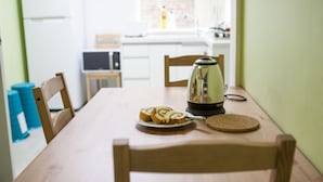 A wooden dining table with a plate of sliced bread and a kettle. - Hans House (Seoul)