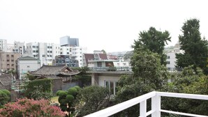 A traditional Japanese building with a modern glass extension, surrounded by lush greenery and other contemporary structures. - Hans House (Seoul)