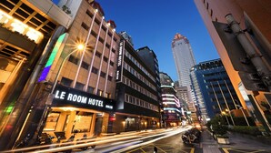 Un hôtel LE ROOM doté d’une façade moderne, de grandes fenêtres et d’une enseigne bien visible.
