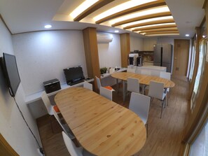Une cuisine moderne avec une table et des chaises en bois, des appareils électroménagers intégrés et un téléviseur à écran plat.