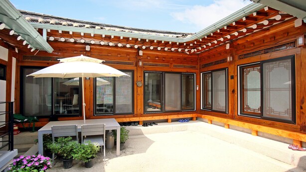 Un edificio tradicional de madera con un patio cubierto, puertas correderas grandes y una mesa con sillas.