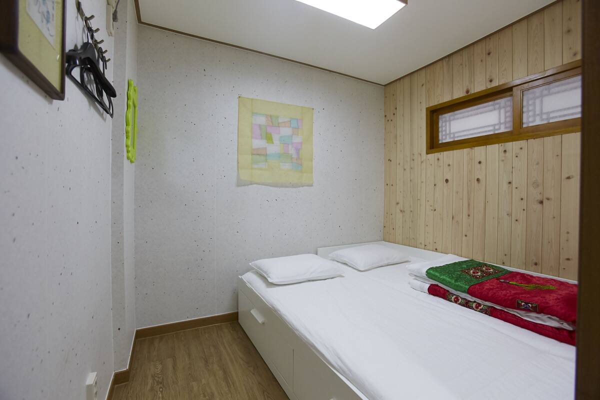 Une chambre à coucher avec un lit, des murs en bois, une fenêtre et une courtepointe.