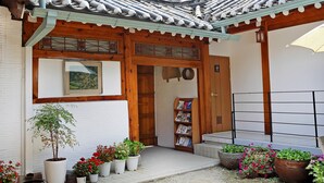 Un edificio japonés tradicional con tejado de tejas, entrada de madera y plantas en macetas.