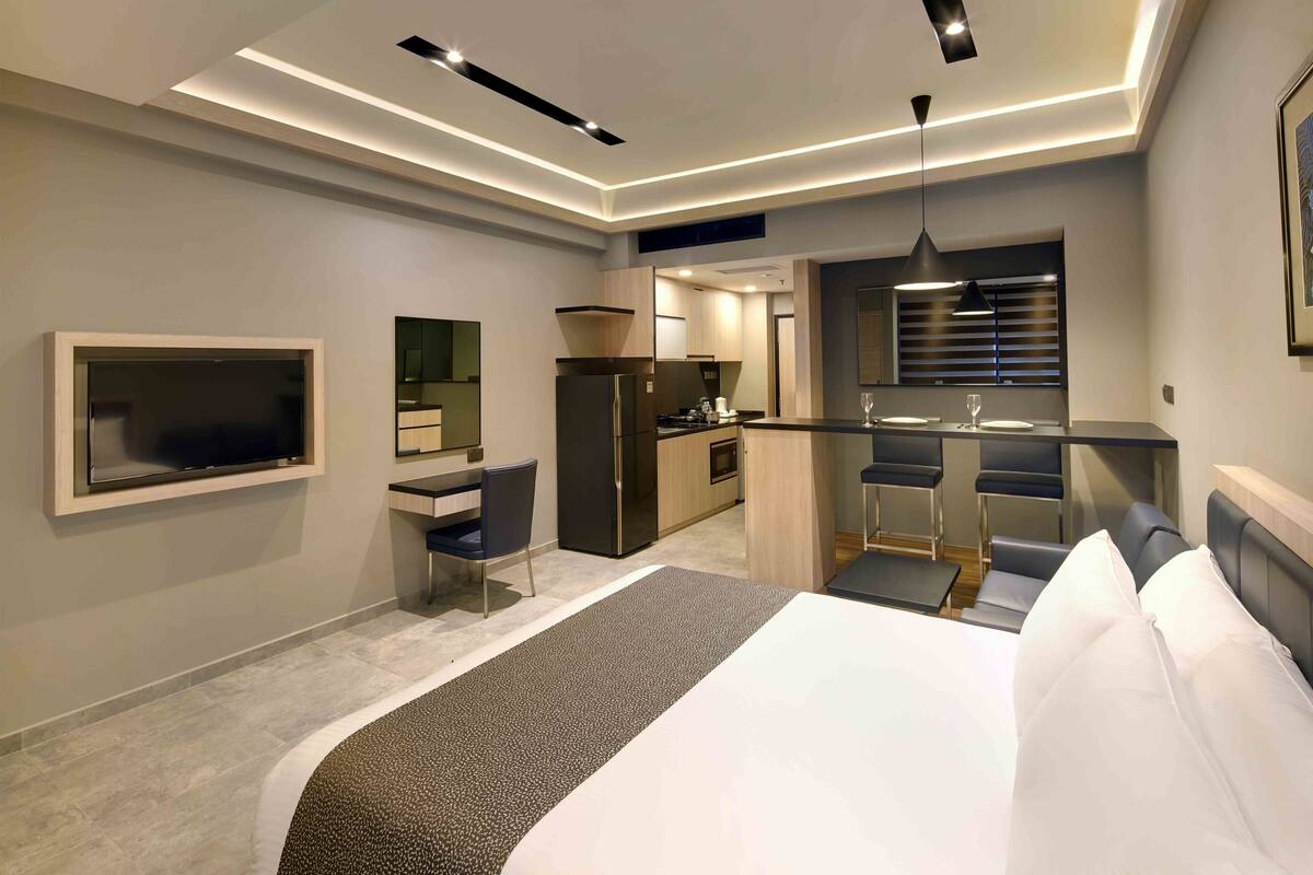 Ein modernes Hotelzimmer mit einem großen Bett, einem Schreibtisch und einer Küchenzeile.