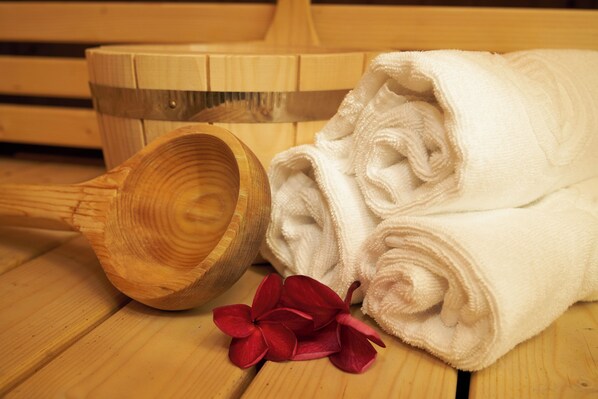 Une baignoire en bois, des serviettes blanches et des fleurs rouges sur un plancher en bois.