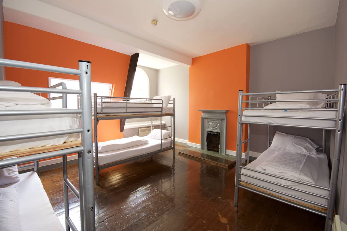 A room with bunk beds, a fireplace, and orange walls.