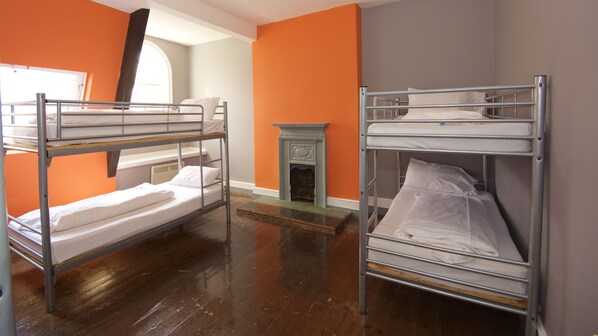 A dormitory room with bunk beds, a fireplace, and orange walls. - Albatross Hostel (Newcastle-upon-Tyne)