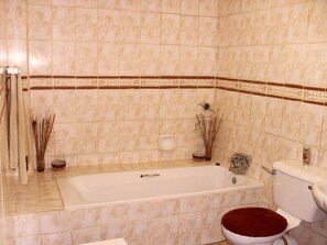 A bathroom with a bathtub, toilet, and a sink. - N4 Guest Lodge (Kgetlengrivier)