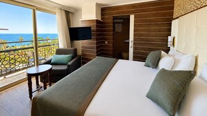 A hotel room with a balcony, a bed, a TV, and a view of the ocean. - Trend Park Hotel (Konyaalti)