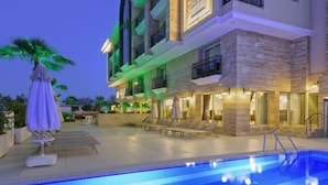 A hotel with a swimming pool, outdoor seating, and a well-lit facade. - Trend Park Hotel (Konyaalti)