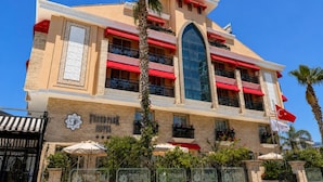 A hotel with a prominent arched window, red awnings, and a sign with a star logo. - Trend Park Hotel (Konyaalti)