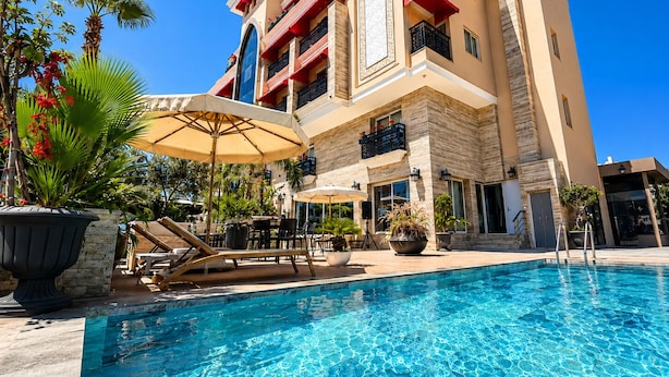 A hotel with a pool, outdoor seating, and a multi-story building with balconies. - Trend Park Hotel (Konyaalti)