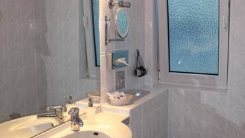 Ein Badezimmer mit einem großen Waschbecken, einer Toilette und einem Fenster mit Strukturglas.