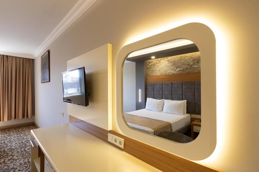 Une chambre d’hôtel avec un lit, une télévision, un miroir et une moquette à motifs.
