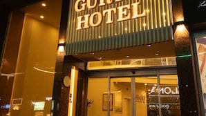 El exterior del Hotel Gürtas, con un llamativo letrero iluminado, grandes ventanales y un diseño arquitectónico moderno.