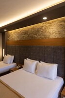 Habitación de hotel con dos camas, un revestimiento de pared con diseño de mármol y un cabecero de madera.