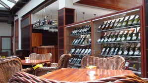 A restaurant interior with wicker furniture, wine racks, and a glass display case.