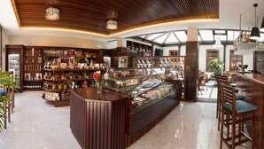 A well-lit, spacious bar area with a variety of bottles and glassware on display, wooden furniture, and a modern ceiling design.