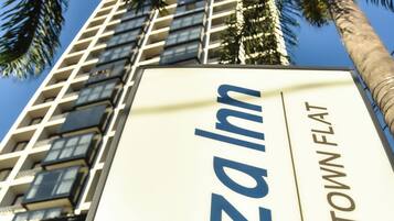 Segnaletica per 'Plaza Hotel' con vista su un palazzo alto e palme.