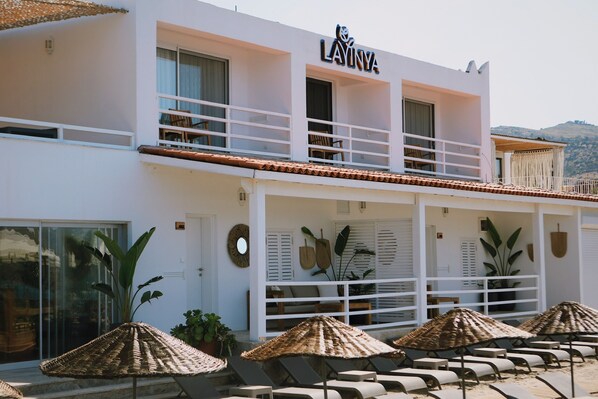 A hotel with a white facade, a balcony with seating, and a covered outdoor seating area with umbrellas. - Lavinya Otel (Bodrum)