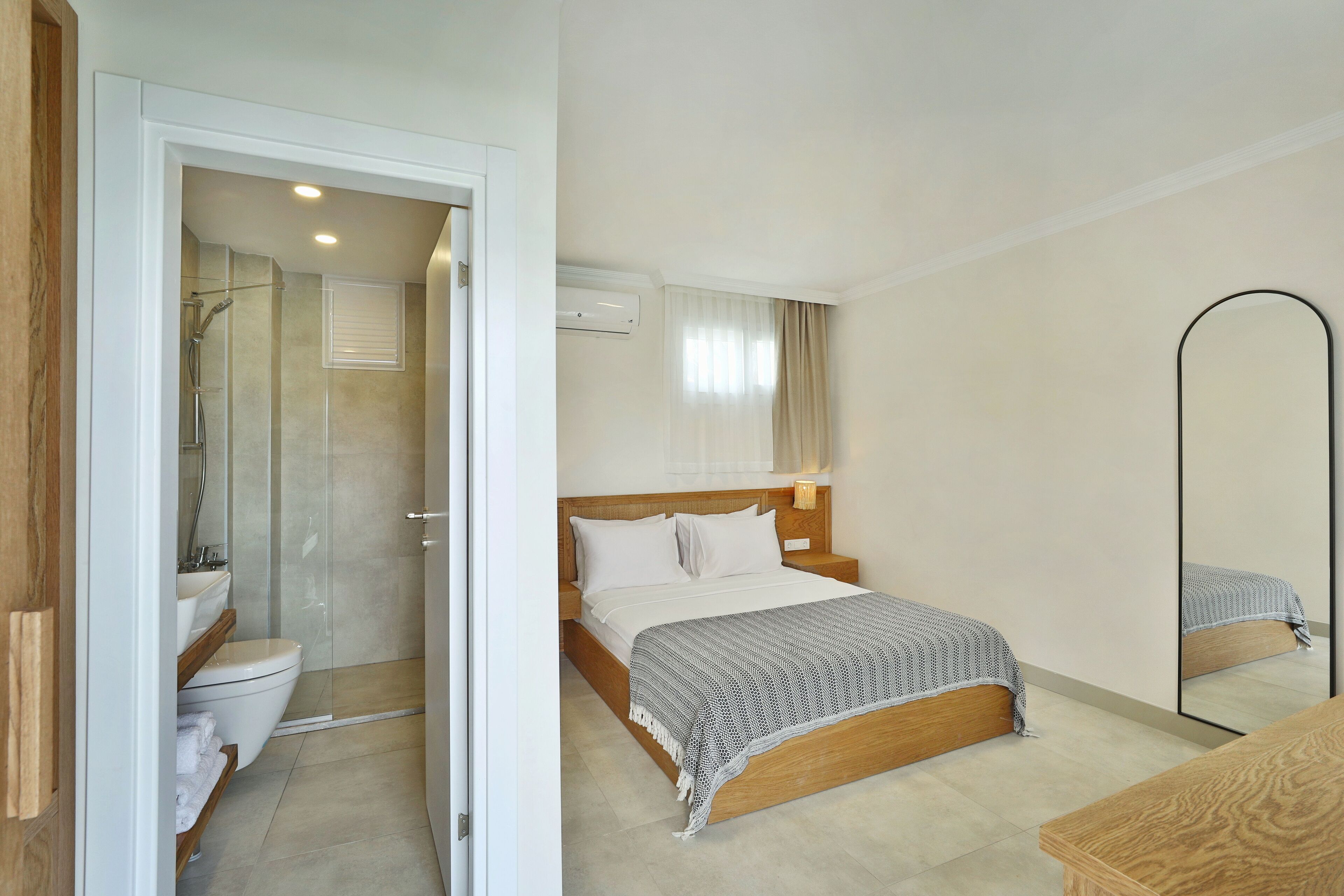 Un dormitorio con cama de madera, ropa de cama blanca, una mesita de noche y un espejo.
