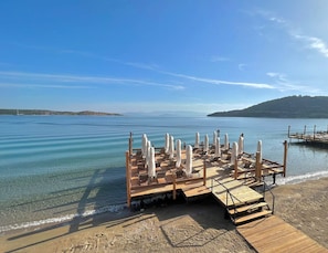 A wooden deck with lounge chairs and umbrellas overlooking a calm body of water. - Lavinya Otel (Bodrum)
