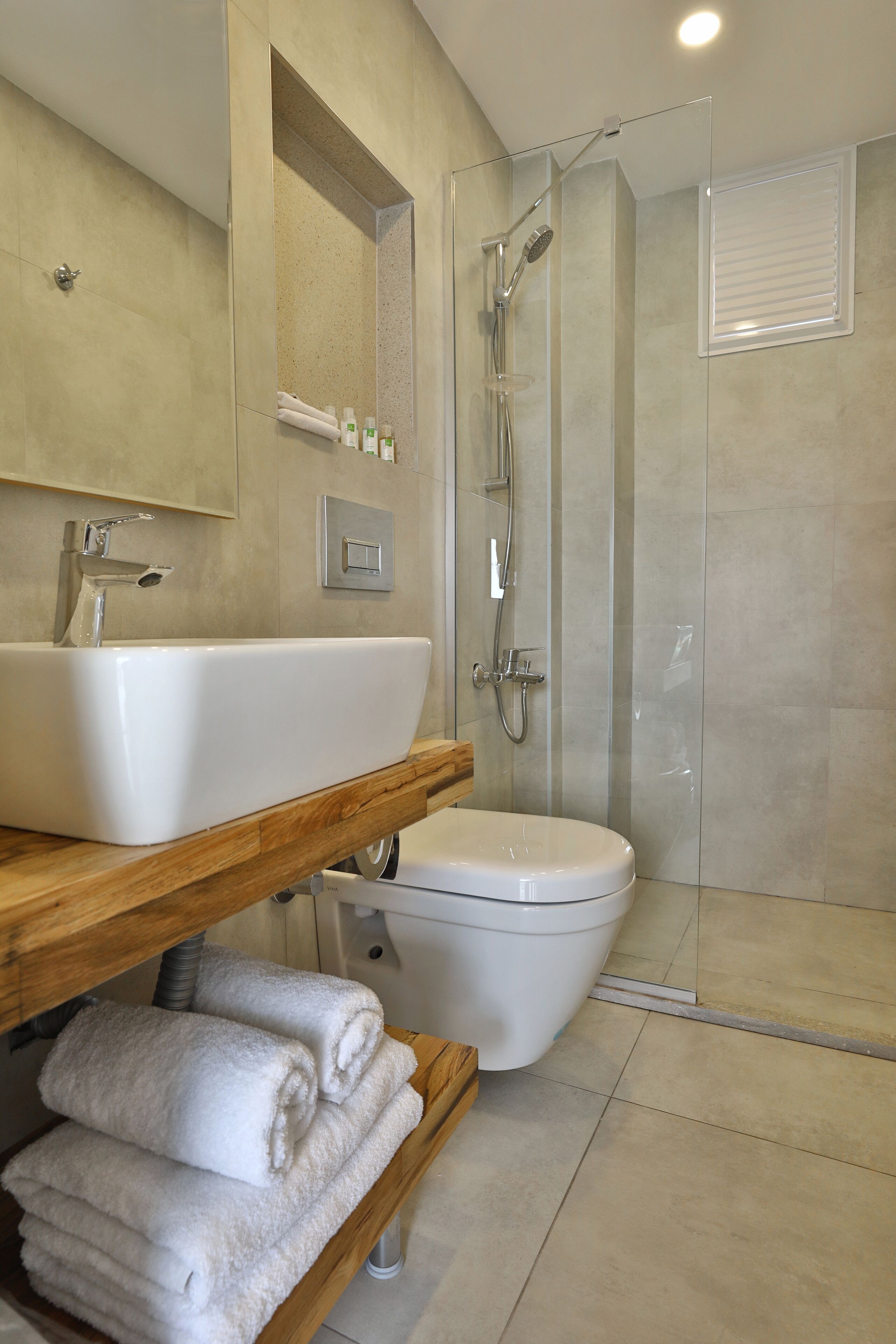 A modern bathroom with a large sink, toilet, and glass-enclosed shower.