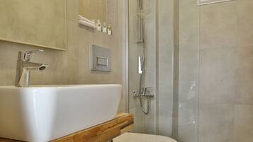 Un baño moderno con un lavamanos grande, inodoro y ducha con mampara de vidrio.