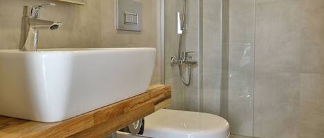 A modern bathroom with a large sink, toilet, and glass-enclosed shower.