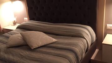 A neatly made bed with a tufted headboard, a bedside lamp, and a nightstand with a small decorative item.