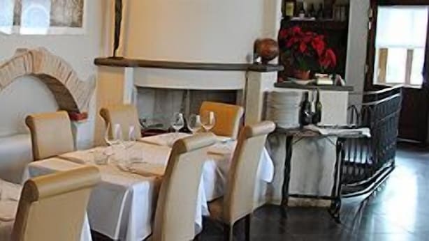En restaurang med en tegelvägg, en öppen spis och en matsal med bord och stolar.